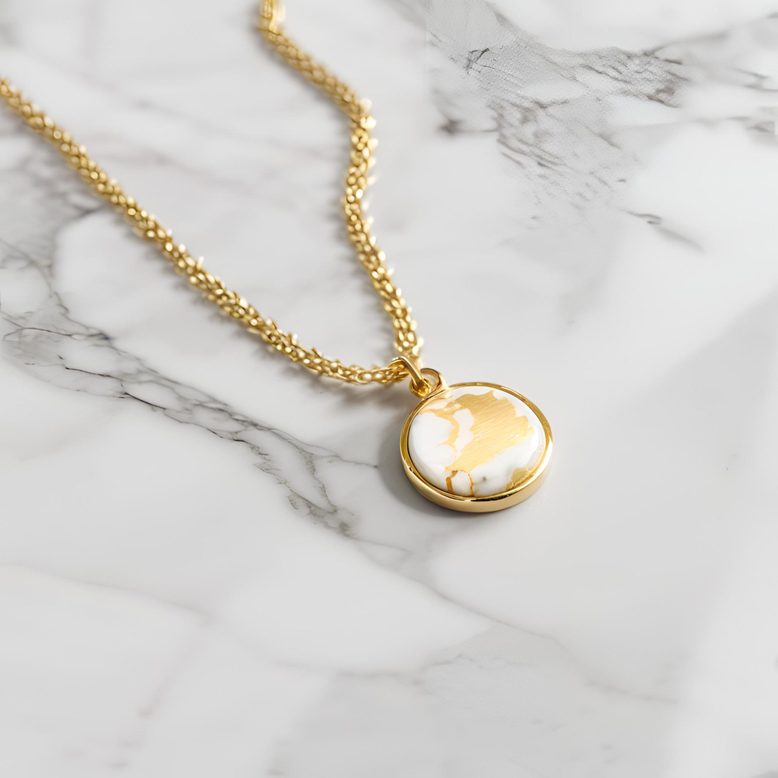 Gold necklace with moon charm on a marble background