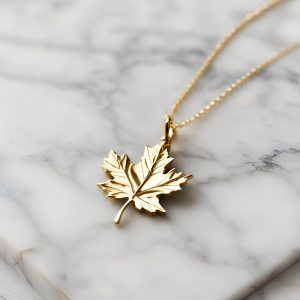 gold necklace with gold maple leaf charm on a white marble background