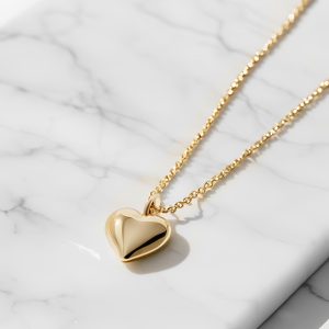 gold chain with gold heart charm on a marble background