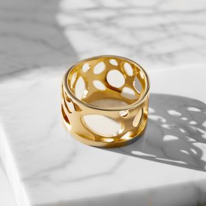 Gold ring with negative space on a marble background